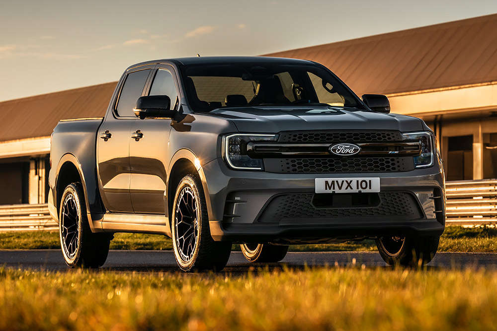Zilveren Ford Pro Ranger Plug-in Hybrid geparkeerd voor een industrieel gebouw.