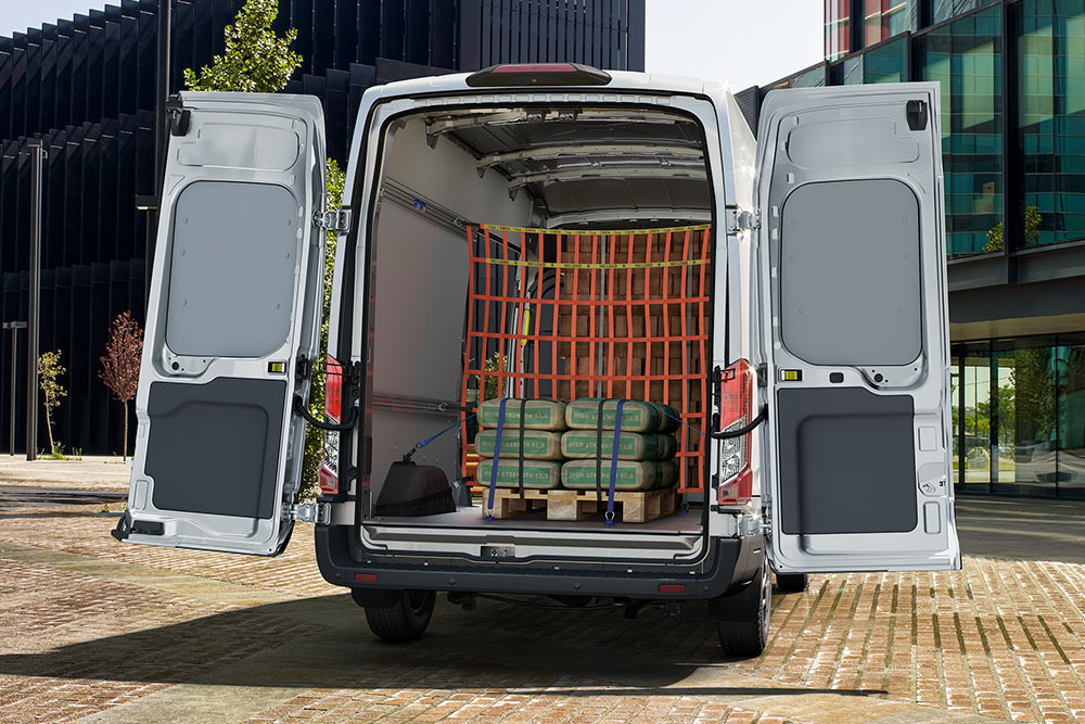  Een achteraanzicht van de binnenkant van een witte Ford bestelwagen geparkeerd nabij kantoorgebouwen.