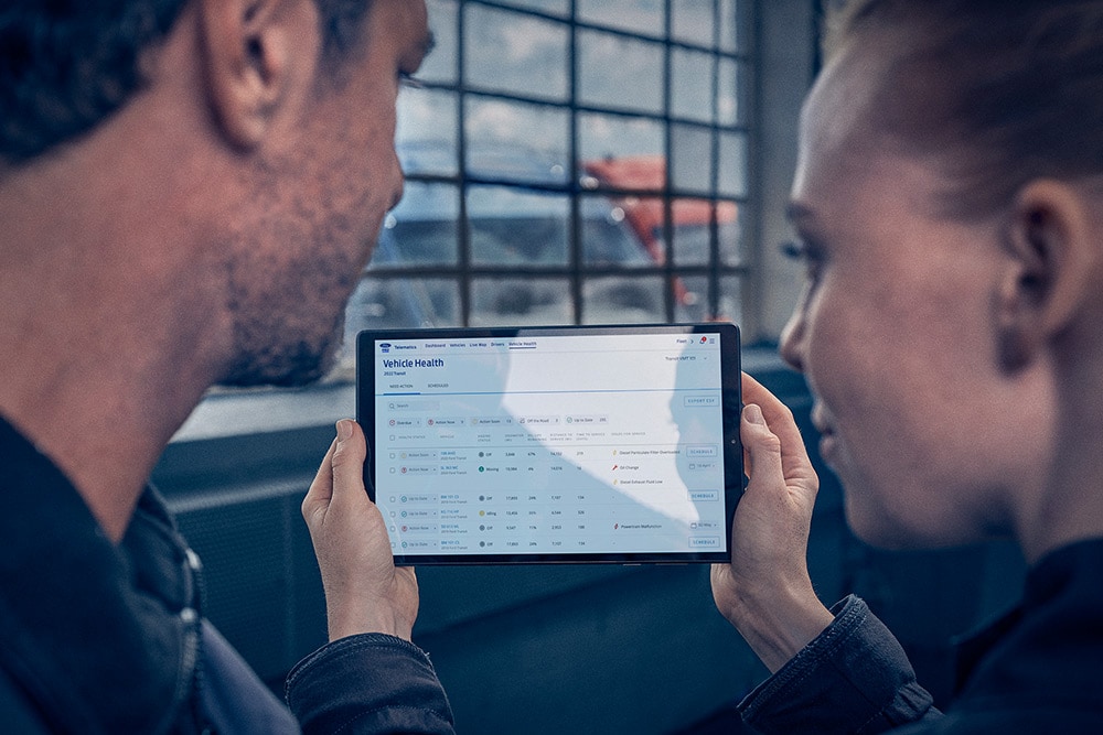  Wagenparkbeheerders bekijken voertuigtelematica op een tablet.