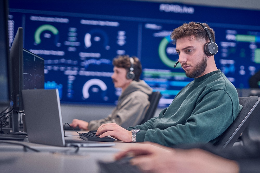 Een Ford-medewerker draagt een headset en werkt op zijn laptop.