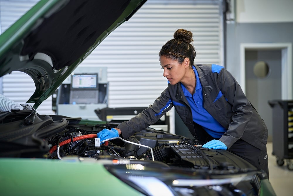 Een monteur van Ford controleert een automotor met de motorkap omhoog in een garage.