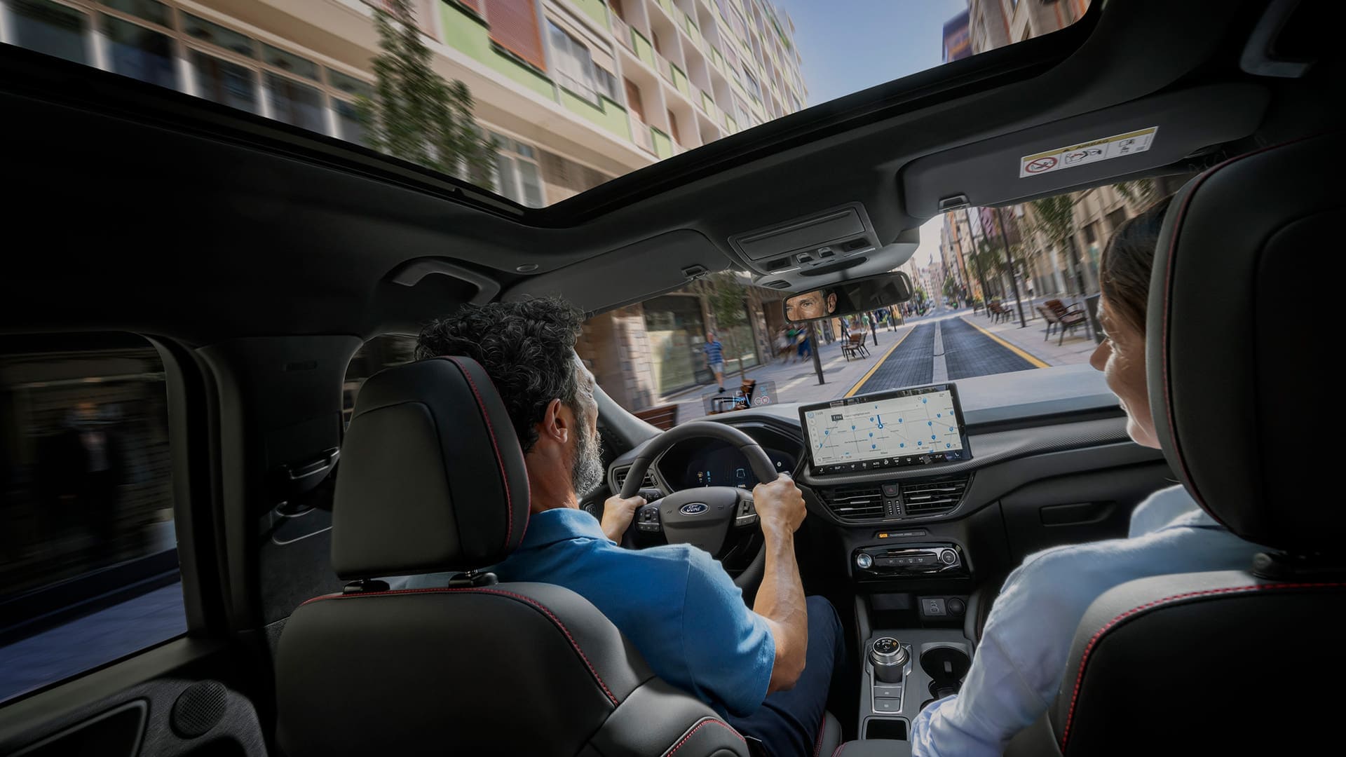 Passagiers in een Ford-voertuig met het digitale SYNC-scherm om te helpen navigeren in de stad.