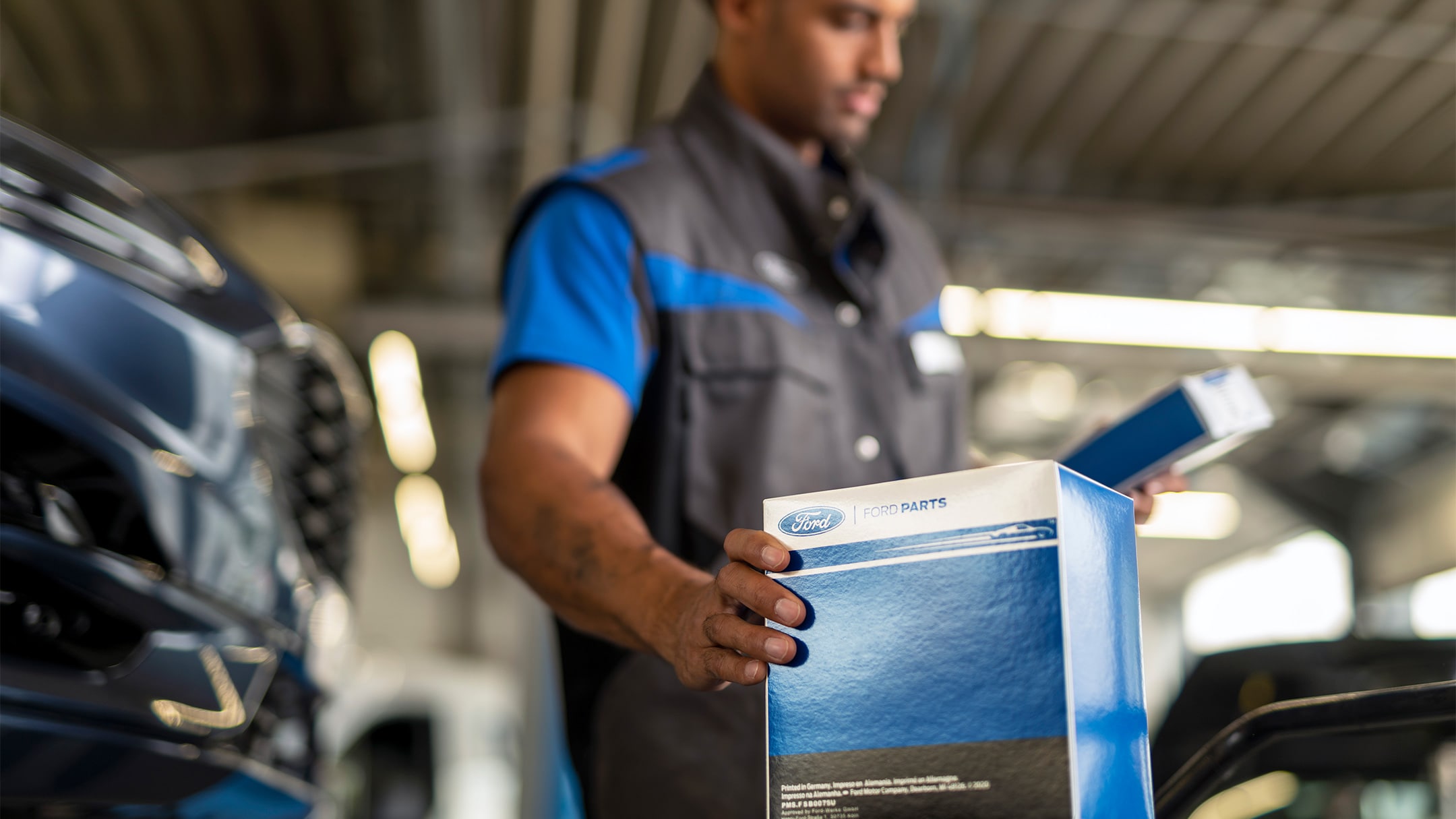 Een monteur in een Ford servicecentrum met een origineel Ford-onderdeel, verpakt in een merkdoos.