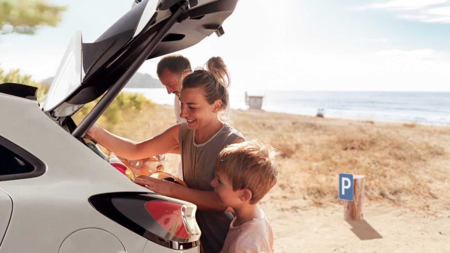 Een gezin aan het strand laadt spullen in de bagageruimte van een Ford-voertuig