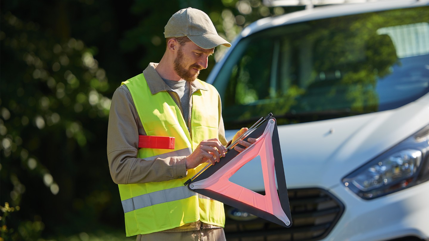 Ford Assistance technician sets up a warning triangle, prioritizing safety during roadside assistance.