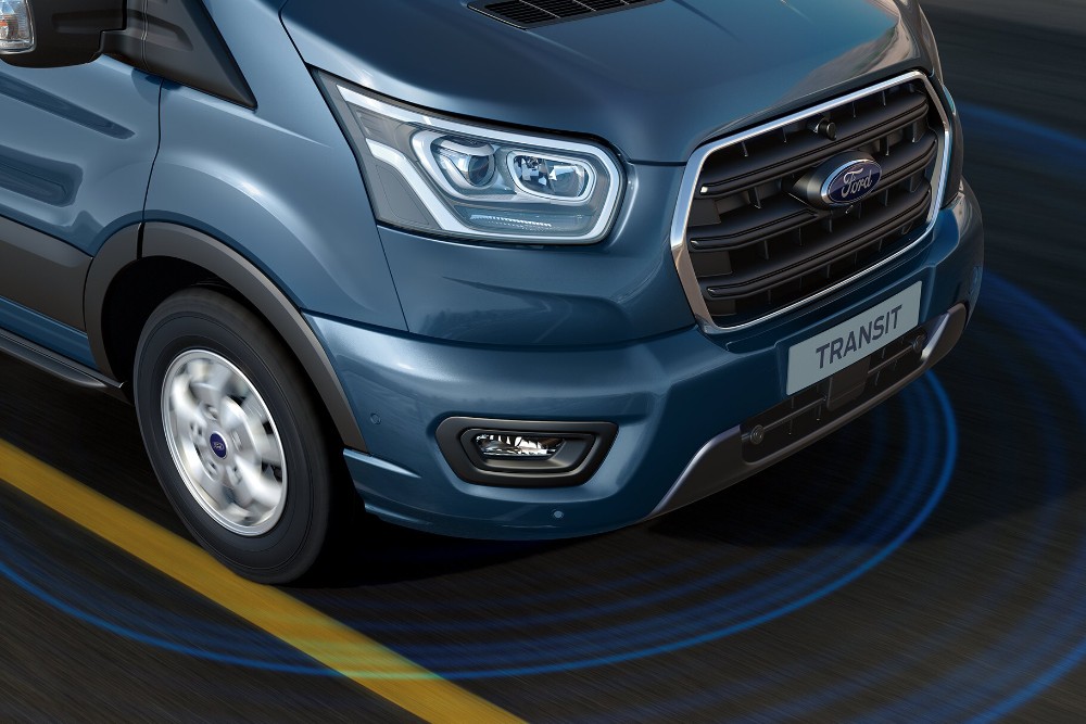Vooraanzicht van een blauwe Ford Transit-bestelbus, met de parkeersensorringen zichtbaar op de grond.